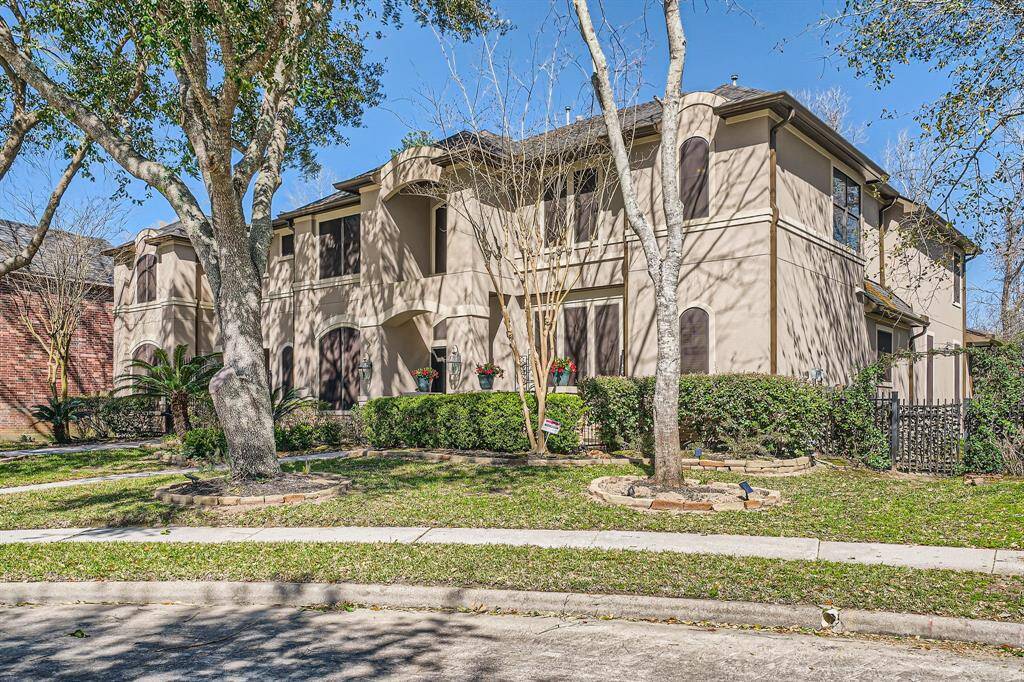 This beautiful two-story home features a stucco exterior with elegant architectural details. Surrounded by mature trees and well-maintained landscaping, it offers a welcoming curb appeal. The property is situated in a quiet, desirable neighborhood.