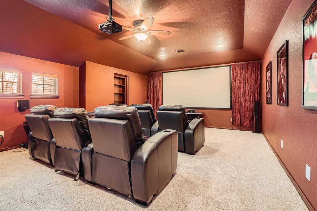 This photo shows a cozy home theater room with plush recliner seating and a large custom screen. The room features warm-toned walls, soft carpeting, and ambient lighting, perfect for an immersive movie-watching experience.