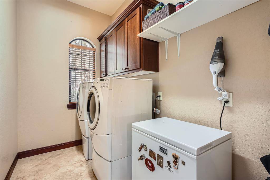 This laundry room has a window for natural light and a neutral color scheme, the washer and dryer stays.