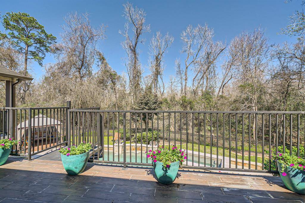 Another view of the backyard from the top level porch featuring a large deck overlooking the beautiful swimming pool and surrounded by a natures preserve offering a serene and private outdoor space.