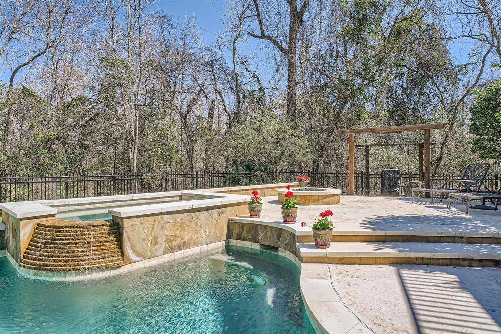 Picture yourself in this luxurious pool and spa, surrounded by lush trees for privacy. The stone patio features decorative planters, a custom made shower to wash off and a fire pit offering a perfect space for relaxation and entertaining.