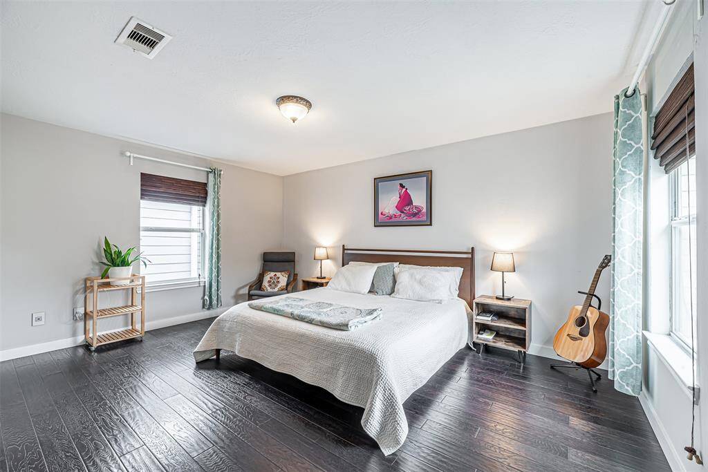 Spcaious primary bedroom with wood floos and plenty of natural lighting