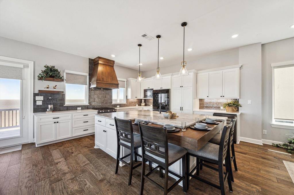 STUNNING ISLAND KITCHEN WITH LEATHERED GRANITE AND QUARTZ COUNTERS AND A DROP-DOWN CORNER BREAKFAST BAR.