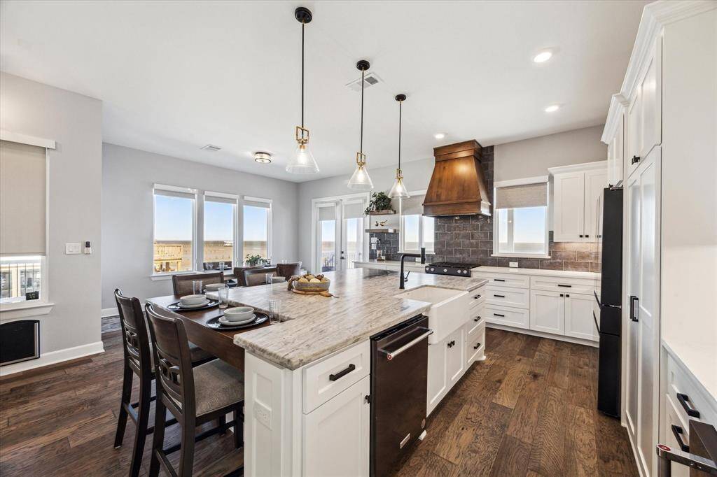 THE KITCHEN ALSO FEATURES CUSTOM FEATURES LIKE THE GRAND WOOD VENT HOOD, SOFT CLOSING CABINETRY AND FLOATING SHELVES.