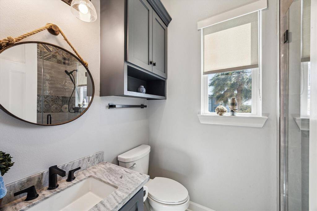 THE FIRST LEVEL BATH FEATURES A WALK-IN SHOWER WITH A BEAUTIFUL FLOOR TO CEILING TILE SURROUND AND GLASS DOOR.