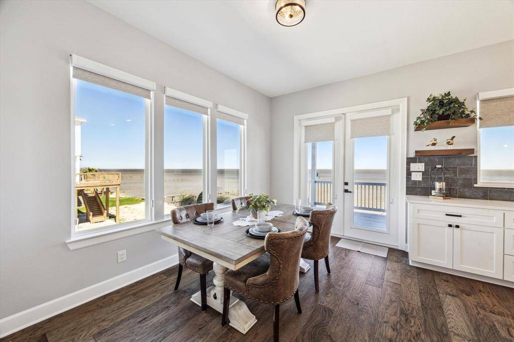 INSIDE, YOU HAVE A CORNER DINING ROOM WITH WOOD FLOORS SURROUNDED BY WINDOWS AND VIEWS OF THE WATER.