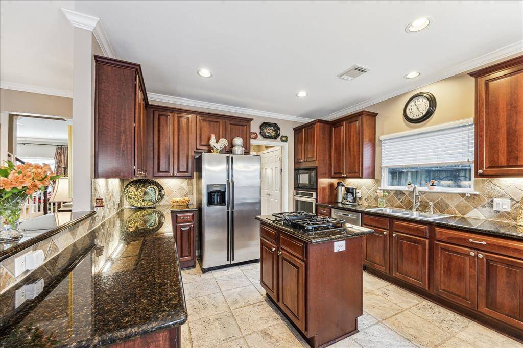 The kitchen shines with granite counters, a central island boasting a gas cooktop, and stainless appliances, a chef’s delight.