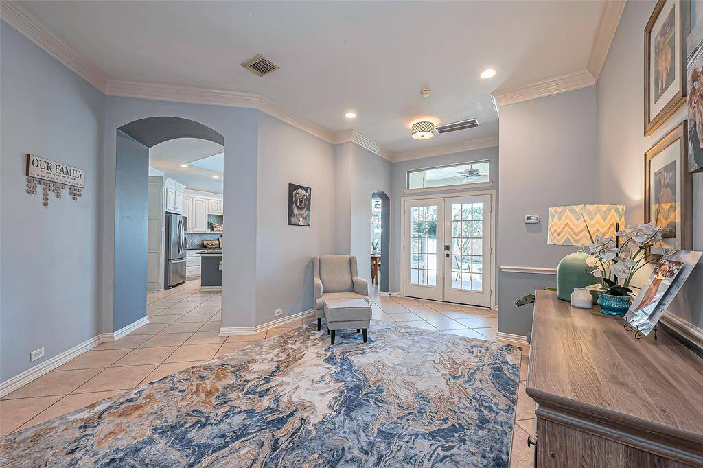 A bright entryway leads to double doors that let in natural light and a view to the backyard. The entry also leads to an open kitchen through an arched doorway, enhancing the home's open and inviting feel.
