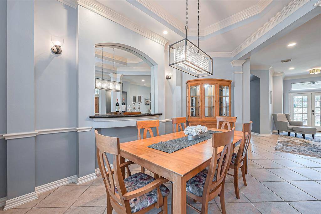 This elegant dining area features a modern chandelier and a built-in bar counter.