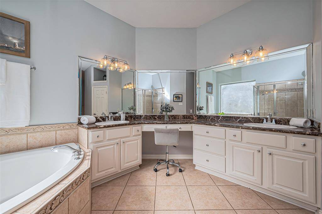 This spacious bathroom features a large vanity with ample storage, dual sinks, and elegant countertops.