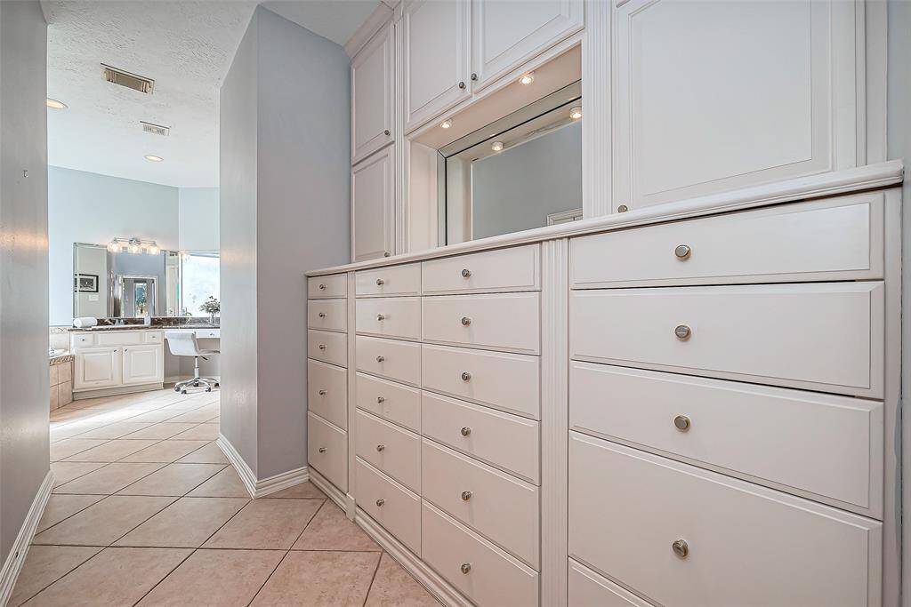 Primary bathroom also offers built-in storage featuring numerous drawers and cabinets.