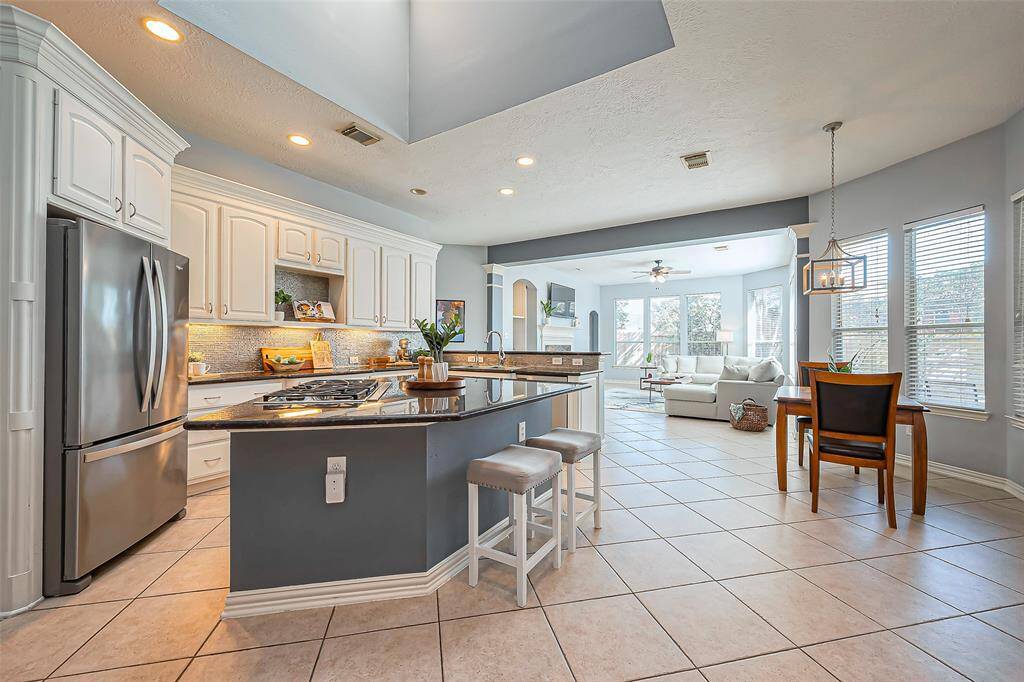 A bright, open-concept kitchen and living area with modern appliances, an island with seating, and a cozy dining nook.