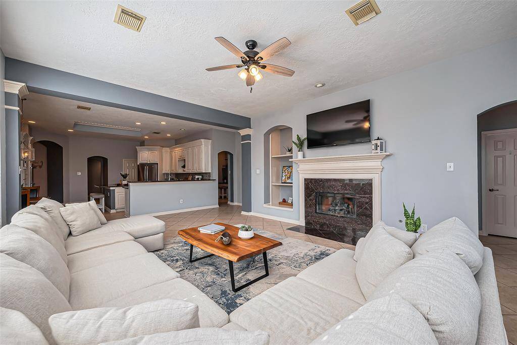 An open layout leading to a modern kitchen. The high ceilings and fireplace creating a welcoming atmosphere.
