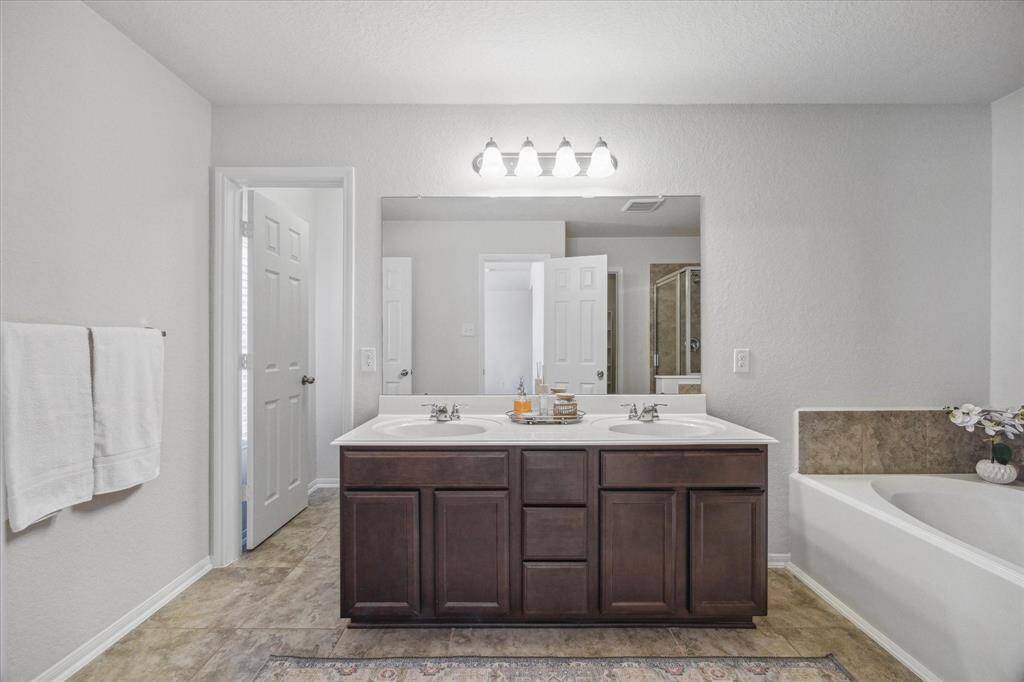 This clean and bright primary en suite bathroom has a separate shower, soaking tub, and double vanities.
