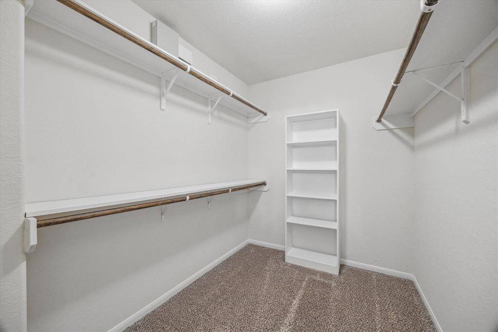 One of two closets located off the primary bathroom with built-in shelving.