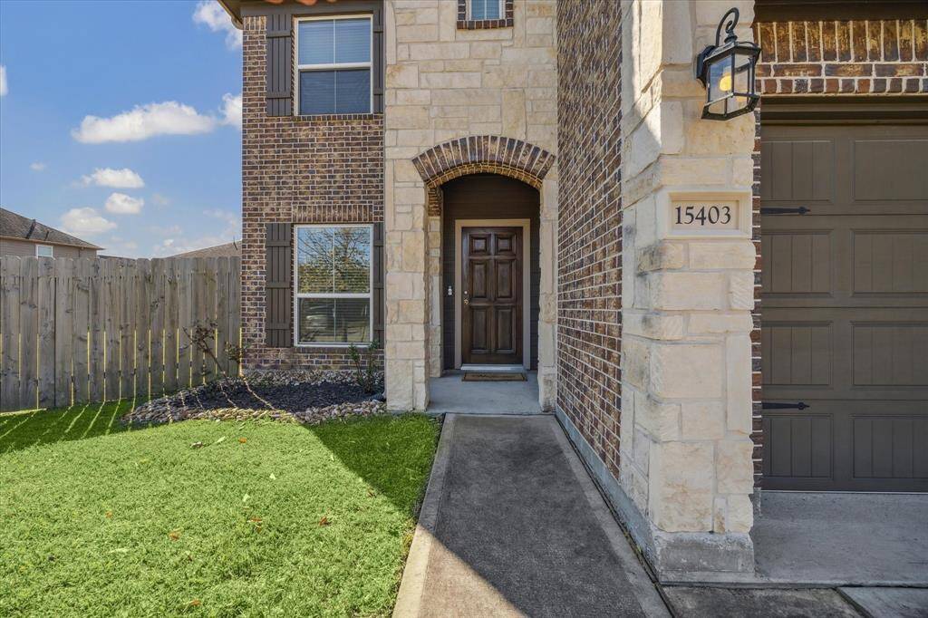 Welcome guests under the covered entry with solid wood door and accent brick work.