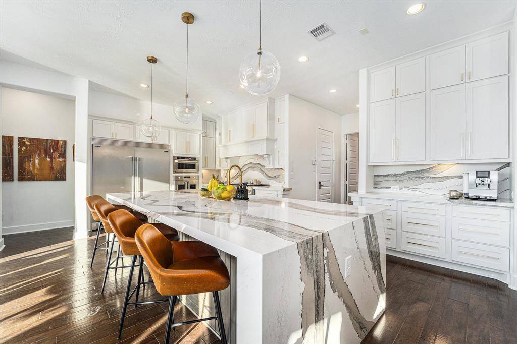 Completely redone kitchen (remodeled recently) w/ custom lighting, new hardware, and freshly painted cabinets, featuring a new oversized 11.5-foot island with quartz waterfall countertops.