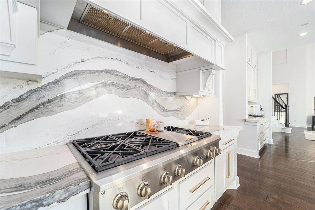 The chef’s kitchen includes top-tier monogram appliances, a 64" double-wide built-in fridge, a double oven with French doors, and a six-burner range with custom vent.