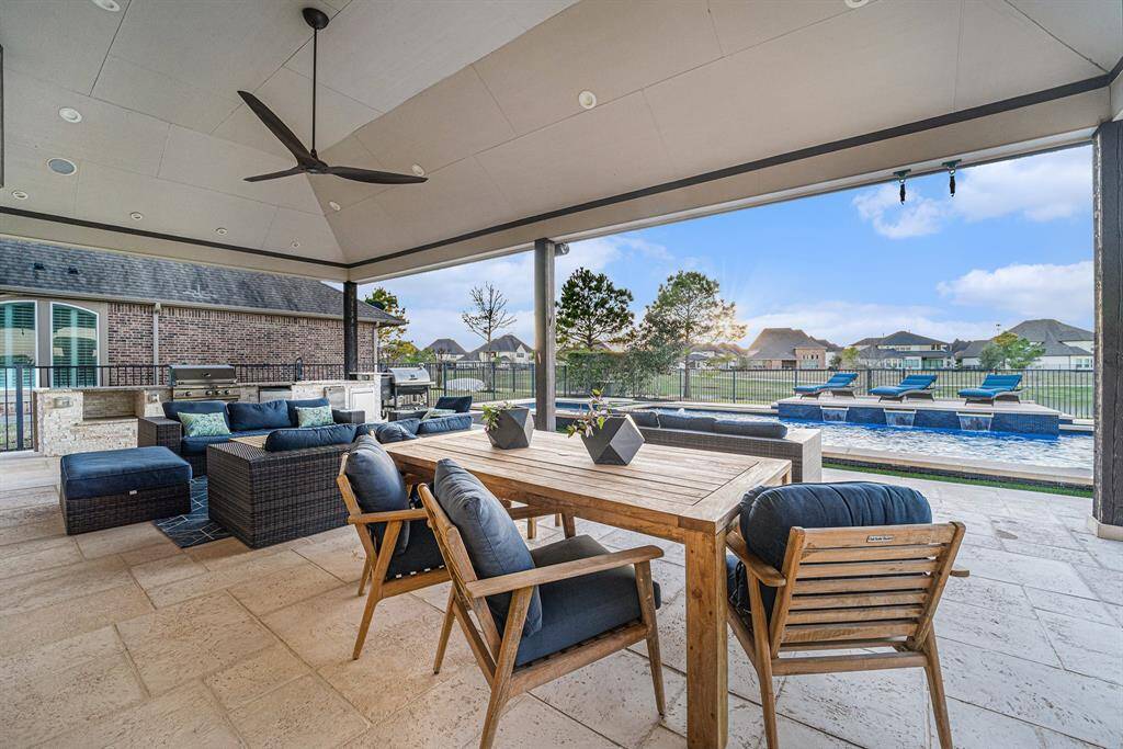 Expansive outdoor patio with a summer kitchen, including a grill, outdoor fridge, ice maker, sink, and plenty of countertop space for hosting and entertaining.