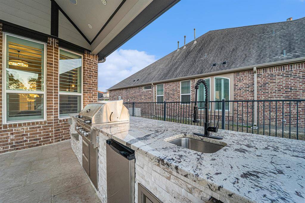 Summer kitchen, wired for TV and surround sound, grill, outdoor fridge, ice maker, sink, countertop storage.