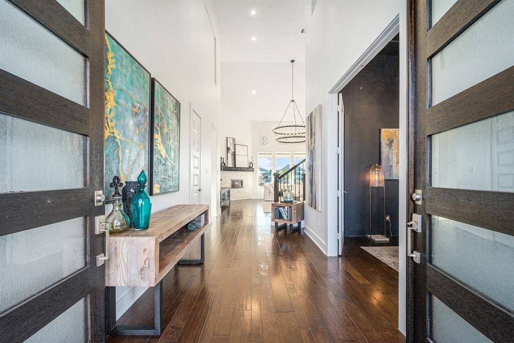 Foyer - A grand foyer with custom lighting, beautiful hardwood floors, and newly finished, double-wide front doors creates an inviting first impression.