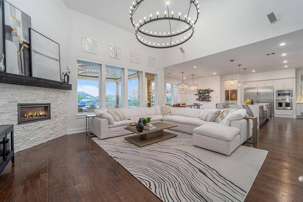 An oversized family room with custom lighting, built-in 7.1 surround sound, and a stunning modern stone fireplace with fire glass accents. Freshly painted in 2022.  Living room boasts Resort and water views, grand staircase, upscale amenities at every turn.  Living room offers breathtaking resort and water views, complemented by a grand staircase that adds elegance and charm to the space.
