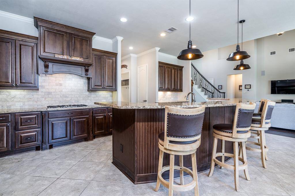 Another view of the expansive kitchen with gorgeous ceramic tile and stained cabinetry that provides ample storage for all of the chef's needs!
