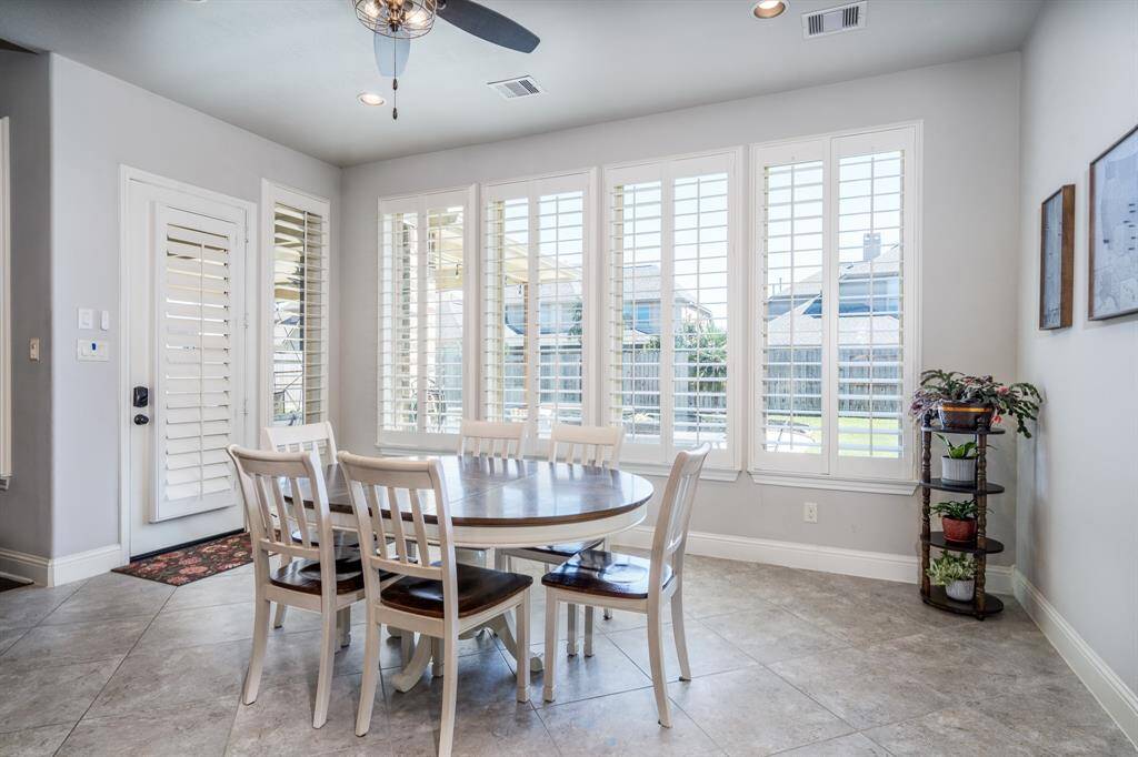 The fabulous casual dining area features plenty of space for your family to gather for special meals! High ceilings and plantation shutters bring warmth and elegance to this space!