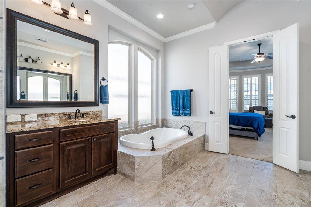 Double doors offer easy access to the primary bedroom from this elegant bath!
