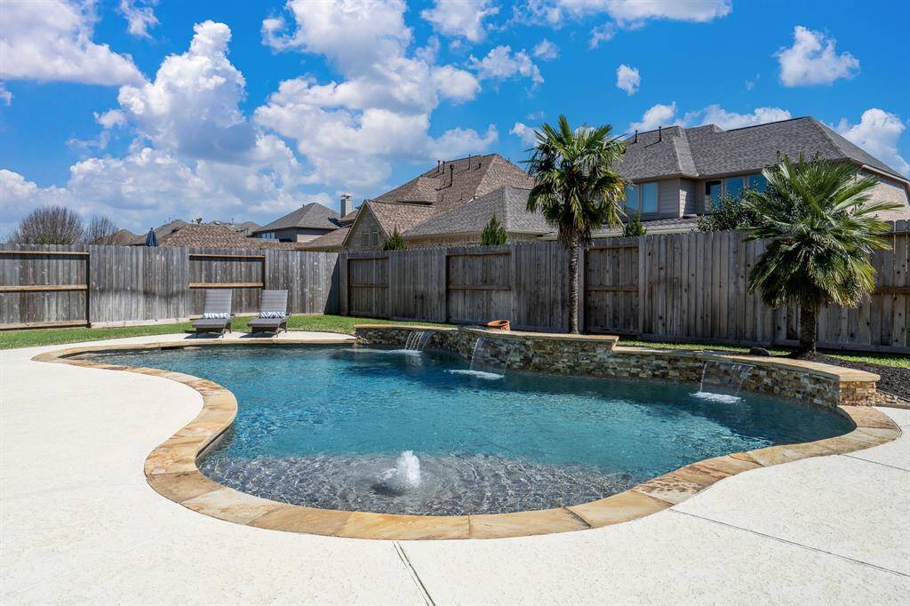 The sparkling pool features a flagstone raised wall with scuffers, pebble sheen and sun ledge with bubbler!