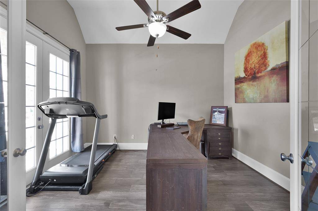 This is the study in the front of the home.  It has a neutral color scheme, wood-style flooring, and large windows with French doors, ideal for a home office or gym.