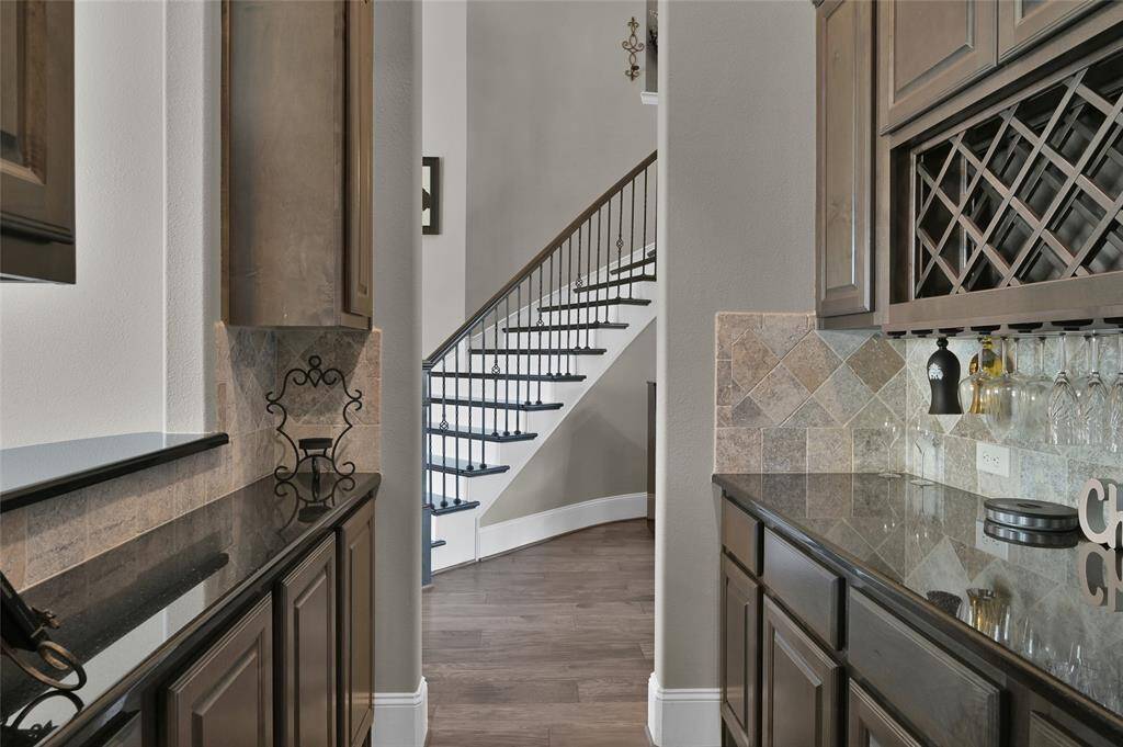 This photo showcases a stylish bar/hostess area with dark wood cabinetry and granite countertops. A wine rack and ample storage are featured, offering a sophisticated and functional space.