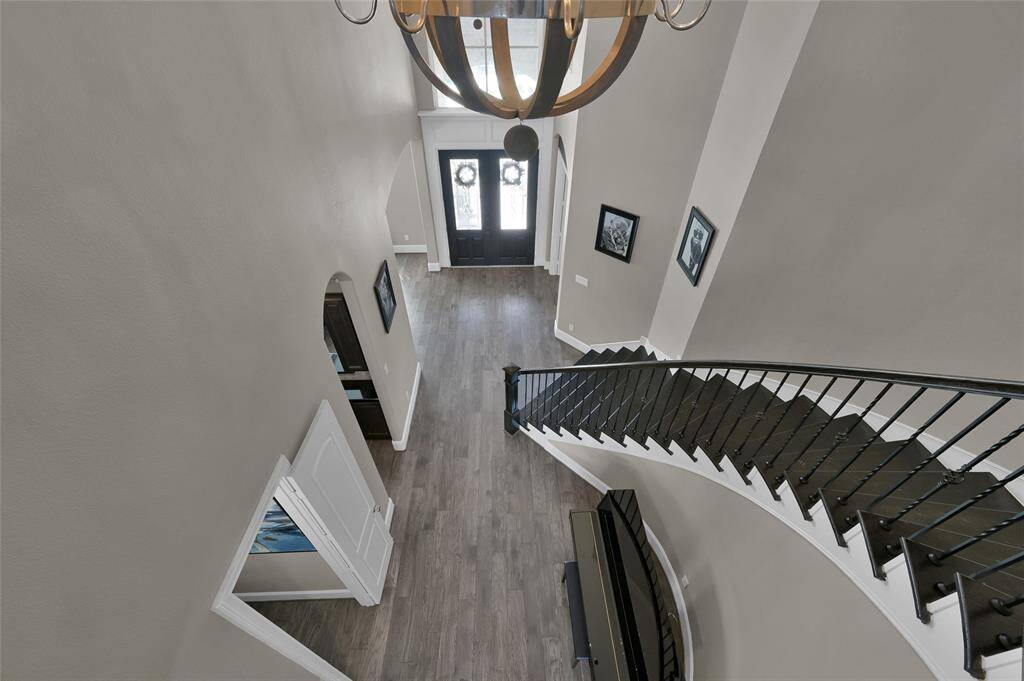 This photo showcases a spacious two-story foyer with a grand staircase and elegant chandelier. The entryway features double doors and wood flooring, creating a welcoming and stylish impression.