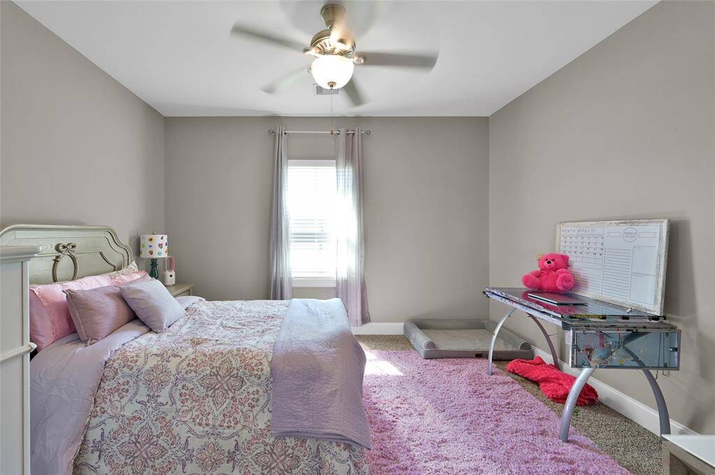 This is one of the additional bedrooms in the great home. This cozy bedroom features soft gray walls, a ceiling fan, and a window with natural light.