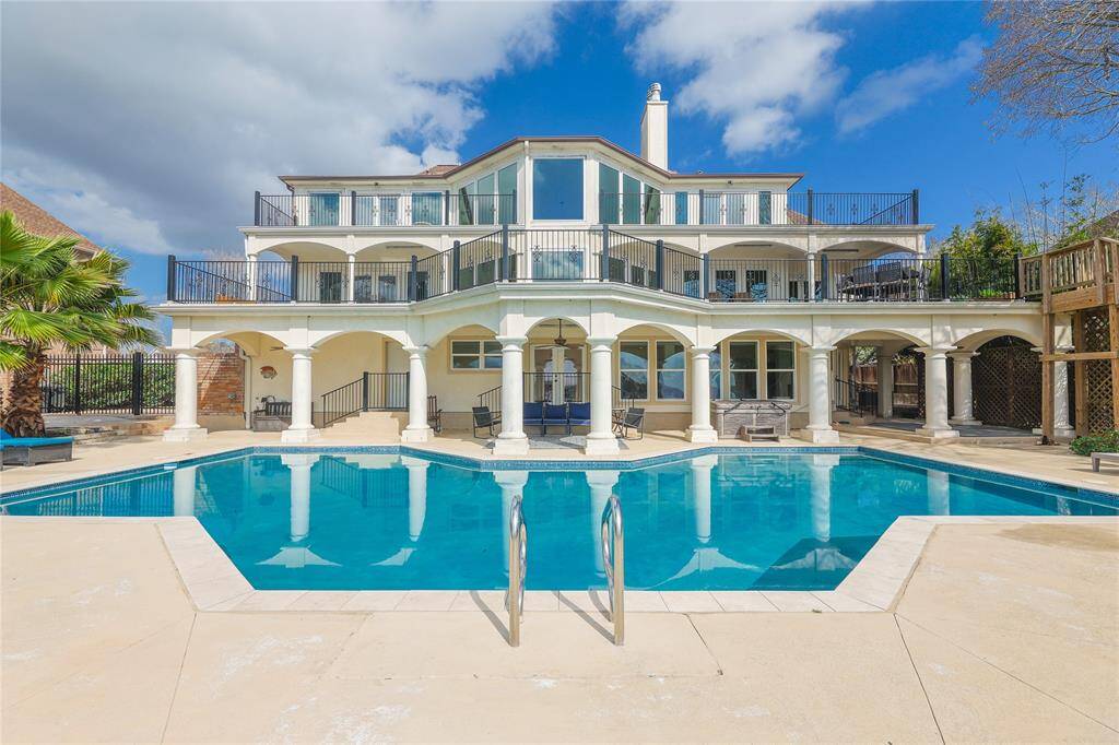 This impressive home features a spacious multi-level layout, overlooking a luxurious swimming pool. The elegant arches and columns add a touch of sophistication, while the expansive patio areas provide ample space for outdoor relaxation and entertainment.