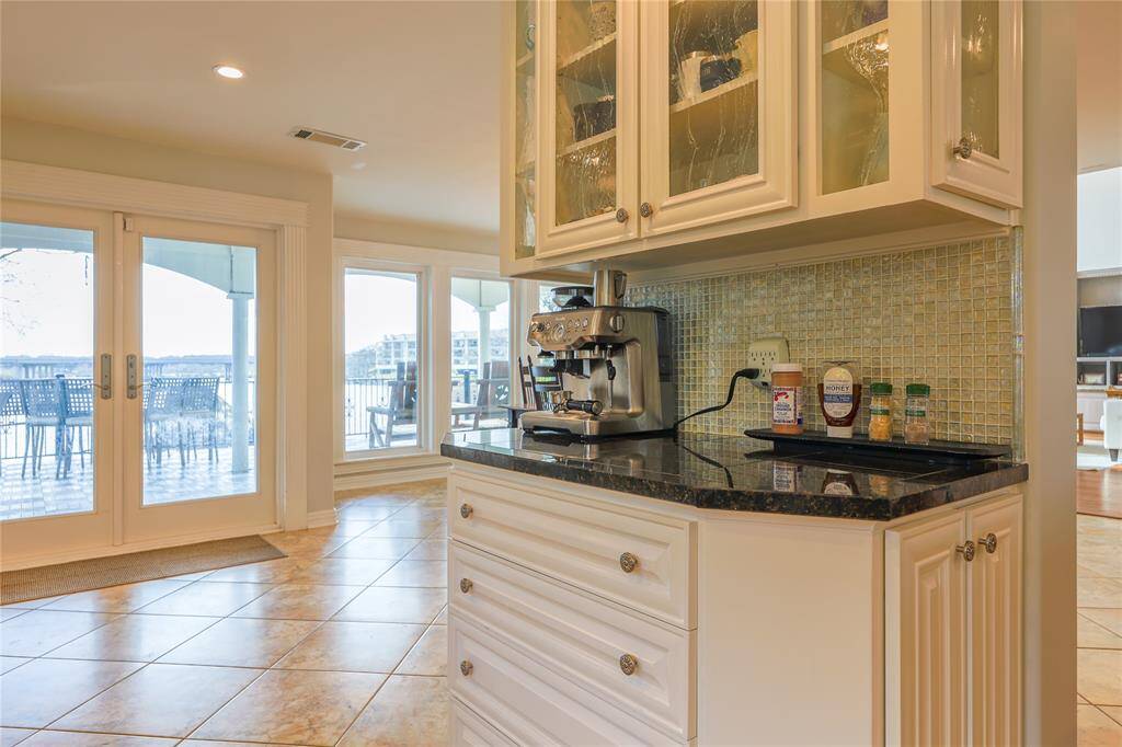 Charming coffee nook with granite countertops, glass-front cabinetry, and a stylish backsplash. Perfect for your morning brew with a view!
