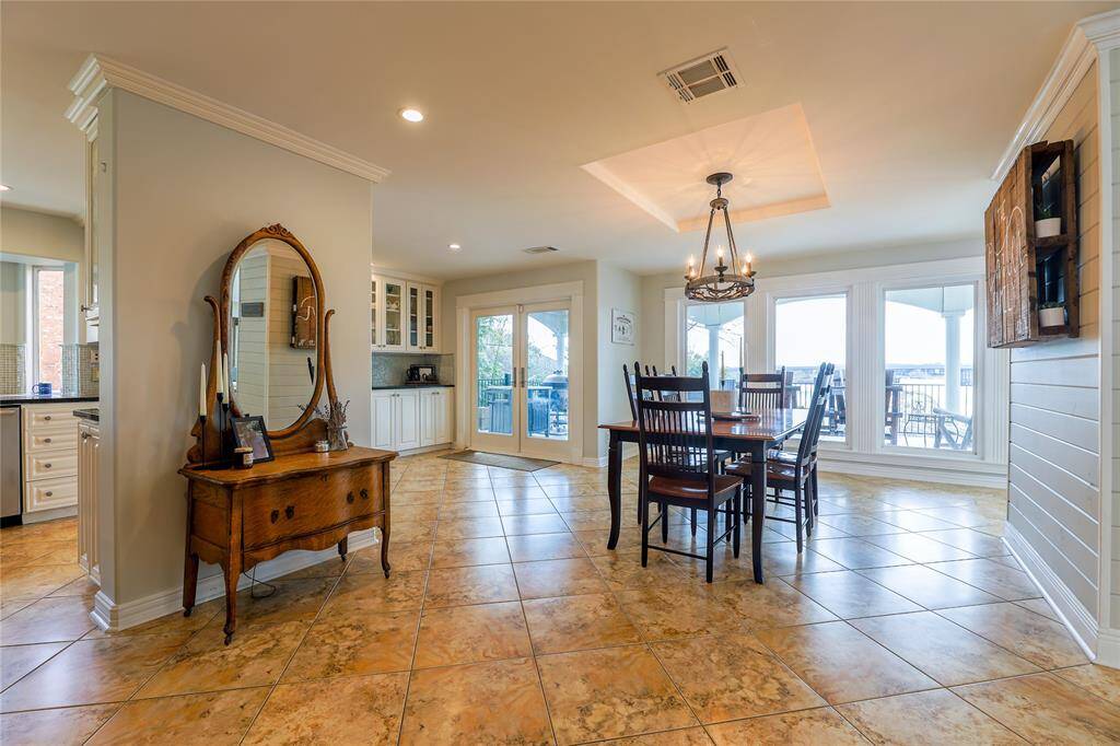 Bright and inviting bedroom with hardwood floors, soft blue walls, and a ceiling fan. It features ample natural light from large glass doors leading to a balcony, and an ensuite bathroom.