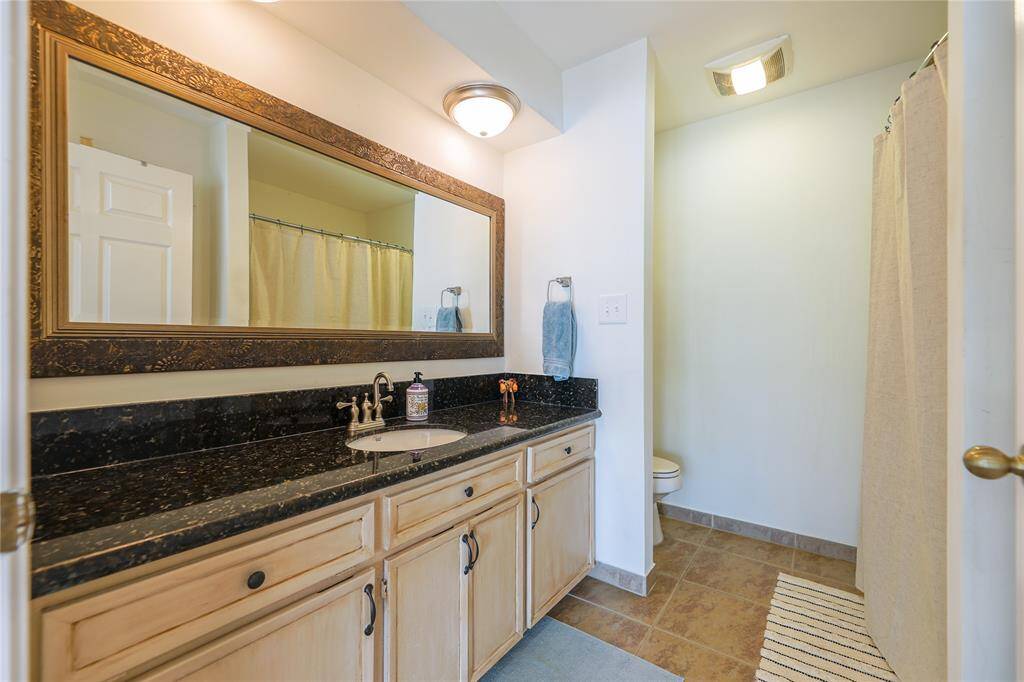 This spacious bedroom features hardwood floors, large windows letting in ample natural light, a ceiling fan, and a cozy bed setup. Just through the sliding glass doors, enjoy a perfect morning/evening on the balcony!