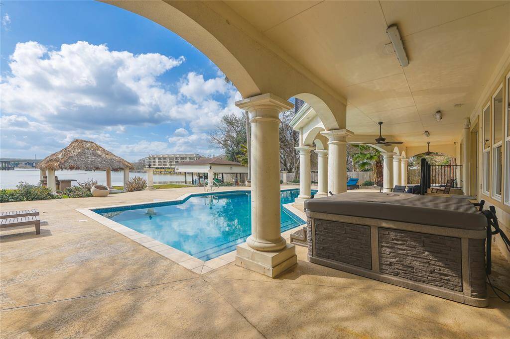 The beautifully landscaped yard includes tall palm trees, a charming thatched-roof gazebo and built-in grill, perfect for outdoor entertaining.