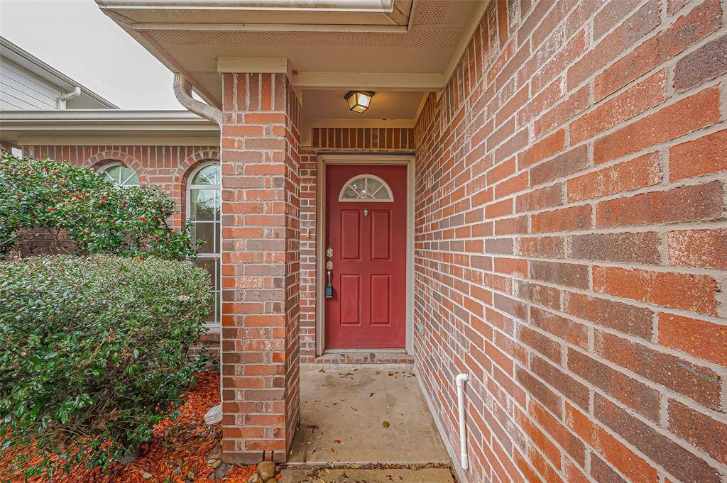 A welcoming walkway leads to the front door, which features a charming half-moon window. A porch light adds warmth and security, while the covered entry provides shelter from the elements—perfect for rainy days or shielding guests from the sun.