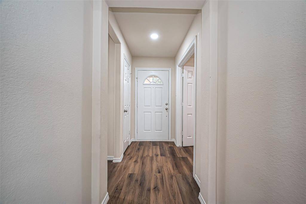 The front door opens to a welcoming foyer with fresh 2024 updates, including recessed lighting and LVP flooring. A convenient coat closet offers storage. To the right, double French doors lead to a private study. To the left, a hallway guides you to two secondary bedrooms, Bath #2, and the utility room, ensuring a functional and well-organized layout..