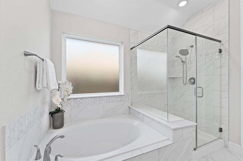 Unwind in the soaking garden tub, perfectly positioned beneath a large window that fills the space with soft, natural light. For a quick refresh, the separate shower offers both convenience and comfort.