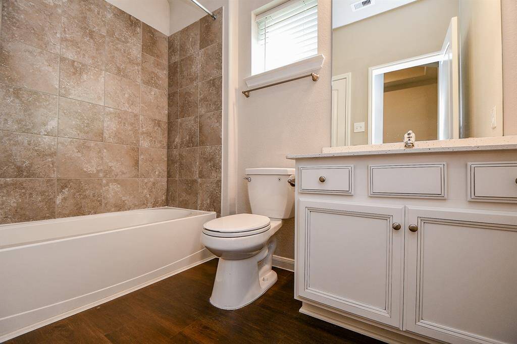 This bathroom features a modern design with a tiled shower and bathtub combo, a sleek vanity with ample storage, and a neutral color palette that provides a clean and inviting atmosphere.