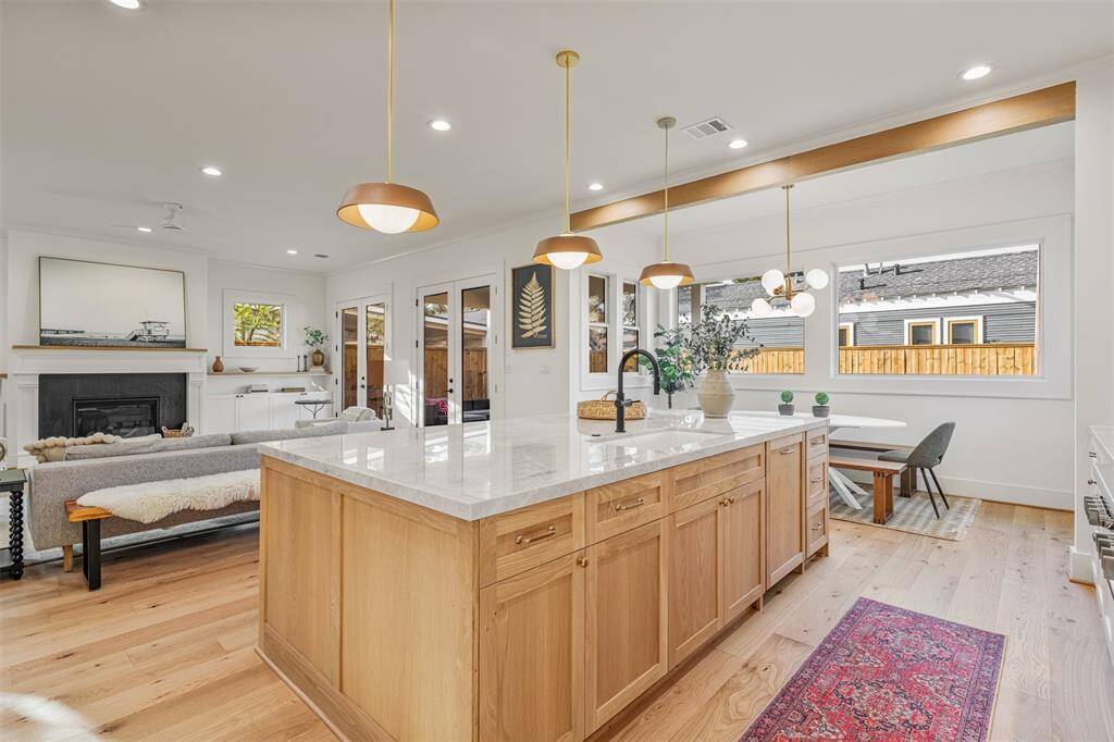 This generously sized island is a showstopper, featuring a breathtaking Taj Mahal quartzite countertop and statement lighting from Rejuvenation.