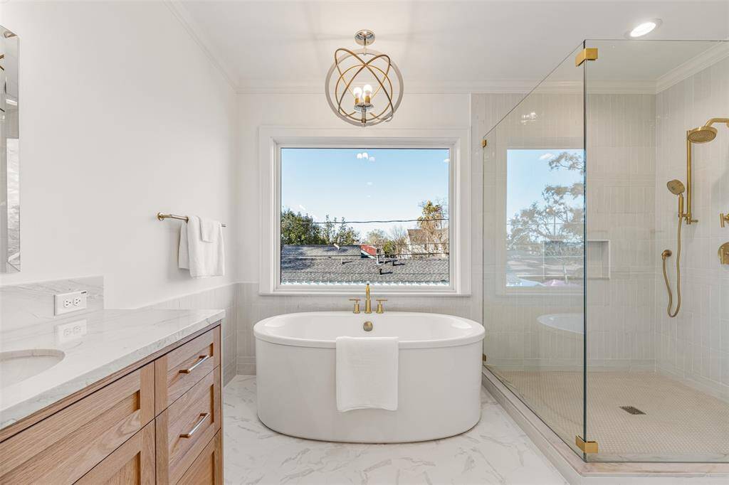 The primary bath is a true retreat, featuring elegant white oak cabinetry, stunning quartzite countertops, and a luxurious Kohler soaking tub.