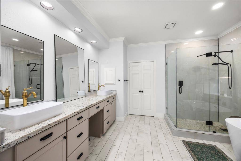 Fully remodeled primary bathroom with frameless shower, freestanding tub, dual sinks, and vanity station.