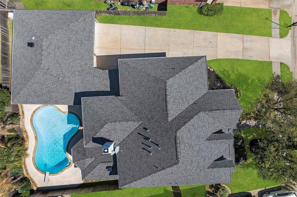 This bird's eyed view shows the long driveway leading up to an amazing garage, the recently installed roof in 2024 and the sparkling pool that will offer years of enjoyment!