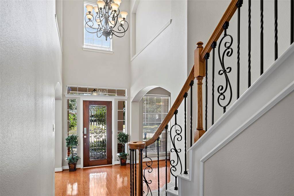 Greet guests with this welcoming view of this fantastic iron staircase and sparkling chandelier above!