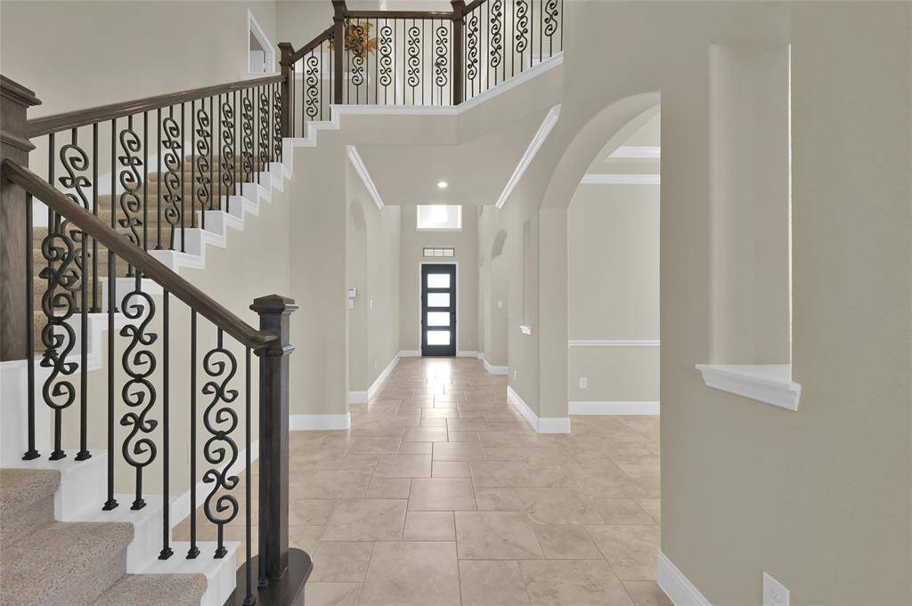 Stunning staircase with rich wood accents with wrought iron railings that lead to your upstairs bedrooms and game-room.