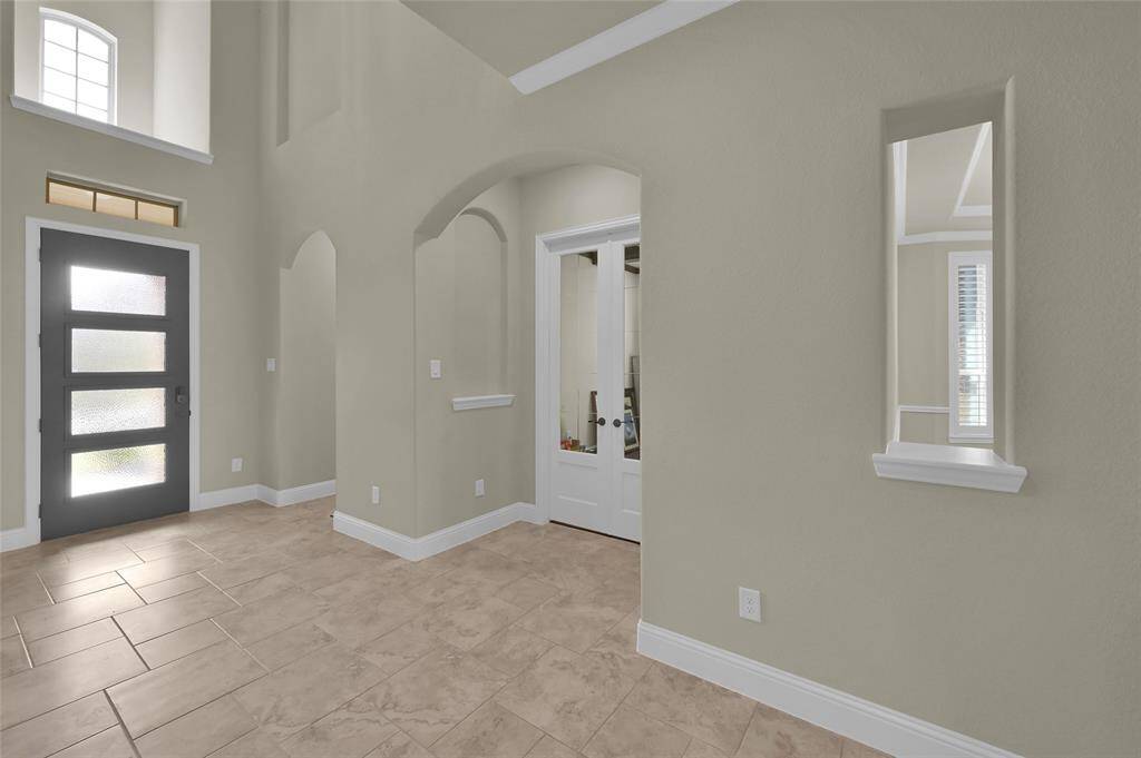 Soaring ceilings give the grandness of this entry. LOADS of archways, tile flooring, art niches, LOTS of custom touches. French doors to your right lead to great office/study!